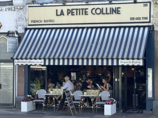 La Petite Colline exterior with blue and white striped awning and pavement terrace